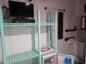 a tv on a shelf in a room with a microwave at Pousada do farol in Jericoacoara