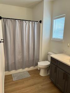 a bathroom with a toilet and a shower curtain at South Charlotte Most Wanted in Charlotte