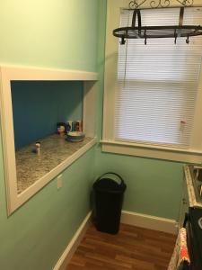 a kitchen with green walls and a window and a trash can at Cozy Bay View OceanSide cottage in Willoughby Beach