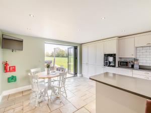 a kitchen with white cabinets and a table and chairs at Horseshoe Cottage in Cottam