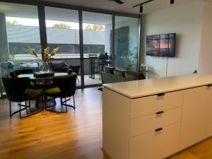 Heart Of Fremantle New Chic Spacious 2 Bed 2 Bath Apartment Very Comfortable, Well Equiped, Great location-Walk to shops restaurants, Bars & Markets 1 King 1 Queen في فريمانتل: مطبخ وغرفة طعام مع طاولة وكراسي