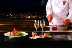 a chef preparing food on a table with glasses of wine at Hotel Nikko Kanazawa in Kanazawa