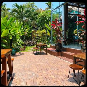 een stenen patio met tafels, stoelen en planten bij The Happy Bird B&B in Hội An