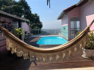 a hammock on a deck with a swimming pool at Casa Aurora Luz do Amanhecer in Rio de Janeiro