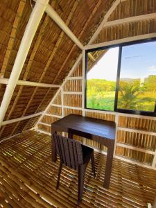 einen Tisch und einen Stuhl in einem Zimmer mit Fenster in der Unterkunft Villa Eliza Ecofarm in Tibiao