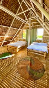 a large room with two beds and a wooden floor at Villa Eliza Ecofarm in Tibiao