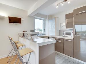 a kitchen with a counter and chairs in it at Studio spacieux 40m² à Anglet : proche plage, piscine, golf, pour 4 pers avec parking et wifi - FR-1-239-685 in Anglet