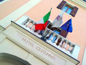 スポレートにあるHotel Clitunnoのバルコニーに二本旗を掲げたホテルの建物