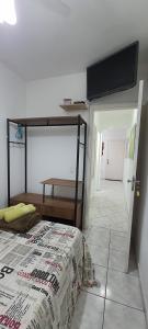 a bedroom with a bunk bed and a tv on the wall at Cantinho do Boris l in Ubatuba