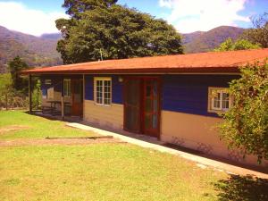 una casa blu e gialla con montagne sullo sfondo di Hostal Casa Pedro Boquete a Boquete