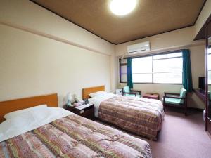 Habitación de hotel con 2 camas y ventana en Sky Heart Hotel Shimonoseki, en Shimonoseki