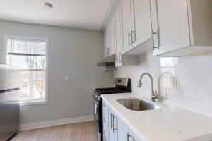 a kitchen with white cabinets and a sink and a window at 3-Bedroom House in Little Italy Downtown-Free Parking in Toronto
