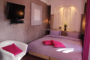 - une chambre avec 2 lits avec des oreillers roses et une télévision dans l'établissement Riad Carllian, à Marrakech