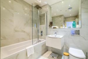a bathroom with a shower tub and a sink and a toilet at Penthouse With Views Of Alexandra Palace in London