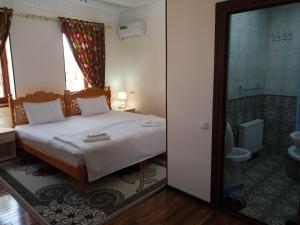 a bedroom with a bed and a bathroom with a toilet at Hotel Mironshox in Bukhara