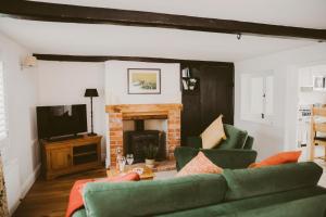 a living room with green furniture and a fireplace at 1 Chantry Cottage in Tunstall