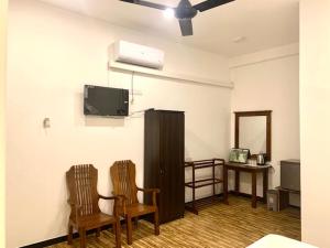 ein Wohnzimmer mit 2 Stühlen und einem Flachbild-TV in der Unterkunft Imperial Resort in Udawalawe