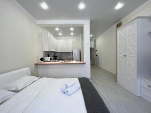 um quarto com uma cama branca e uma cozinha em Апартаменты в элитном ЖК em Pavlodar
