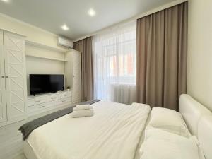 um quarto com uma grande cama branca e uma televisão em Апартаменты в элитном ЖК em Pavlodar
