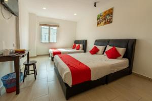 1 dormitorio con 2 camas con almohadas rojas y escritorio en MRJ Hotel Wakaf Che Yeh 1, en Kota Bharu