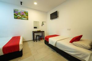 Habitación con 2 camas y mesa. en MRJ Hotel Wakaf Che Yeh 1 en Kota Bharu