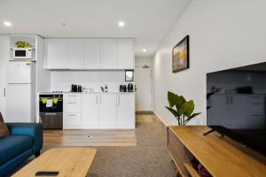een woonkamer met een blauwe bank en een keuken bij 1 Bedroom City Base with Free Car Park in Christchurch