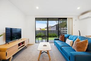 een woonkamer met een blauwe bank en een tv bij 1 Bedroom City Base with Free Car Park in Christchurch