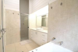 a white bathroom with a shower and a sink at Beach Haven in Merimbula +10 photos