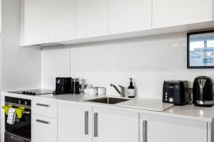 een witte keuken met witte kasten en een spoelbak bij 1 Bedroom City Base with Free Car Park in Christchurch