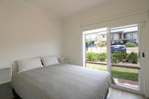 ein weißes Schlafzimmer mit einem Bett und einem großen Fenster in der Unterkunft Beach Haven in Merimbula