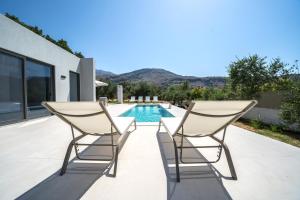 un par de sillas en un patio con piscina en Villa Vivian Heated Private Swimming Pool & Jacuzzi, en Georgioupolis