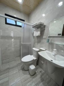 a white bathroom with a toilet and a sink at Islandlife B&B in Huxi
