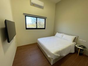 a small bedroom with a white bed and a window at Islandlife B&B in Huxi