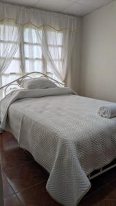 a bed with a white comforter and a window at La casita in Cochabamba