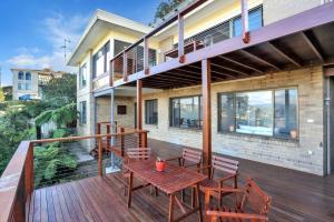 a wooden deck with a table and chairs on a house at Aqua La Vista - 4 Bedroom Pet Friendly House in Merimbula