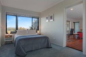 a bedroom with a bed and a large window at Aqua La Vista - 4 Bedroom Pet Friendly House in Merimbula