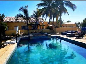 una piscina frente a una casa con palmeras en Mystic Breeze, en El Pescadero