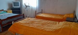 a bedroom with two beds with orange sheets and a television at Supernova - Gualeguay in Gualeguay