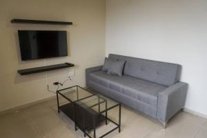 a living room with a couch and a tv at Hermoso Apartamento Cerca de la Embajada Americana in Santo Domingo