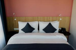 a bedroom with a large bed with black and white pillows at Graf Hotel in Shymkent