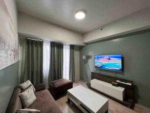 a living room with a couch and a tv on the wall at 2 BR Condo Jazz cozy at best deal! in Manila