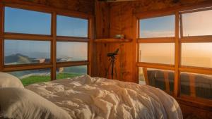 a bedroom with a bed and windows with a camera at Matai Peak Lodge in Hundalee