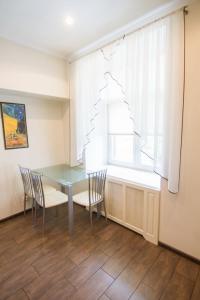 ein Esszimmer mit einem Tisch, Stühlen und einem Fenster in der Unterkunft Pechersky Kvartal Apartments in Kiew