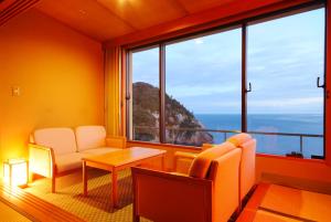 a room with a table and chairs and a large window at Hotel Kinparo in Toyooka