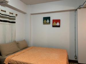 ein Schlafzimmer mit einem Bett und zwei Bildern an der Wand in der Unterkunft Chiangmai HomeTeL in Chiang Mai