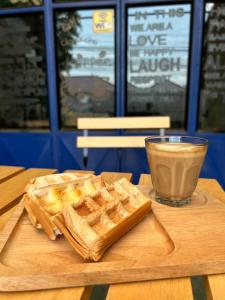 a wooden table with a plate of waffles and a cup of coffee at Chiangmai HomeTeL in Chiang Mai