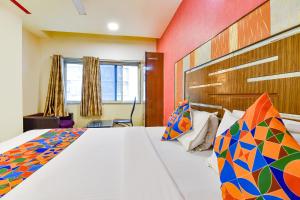 a bedroom with a large bed with colorful pillows at FabHotel Kadamb Inn in Ahmedabad