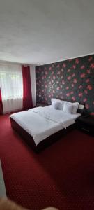 a bedroom with a large bed with a floral wallpaper at VILA DAVISON in Târgu Jiu