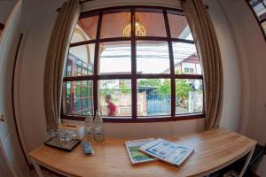 a table in a room with a large window at Baan Hall Hostel in Khon Kaen
