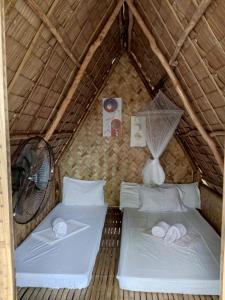 a room with two beds in a thatch roof at Akoya Beach Sunset Camp in El Nido